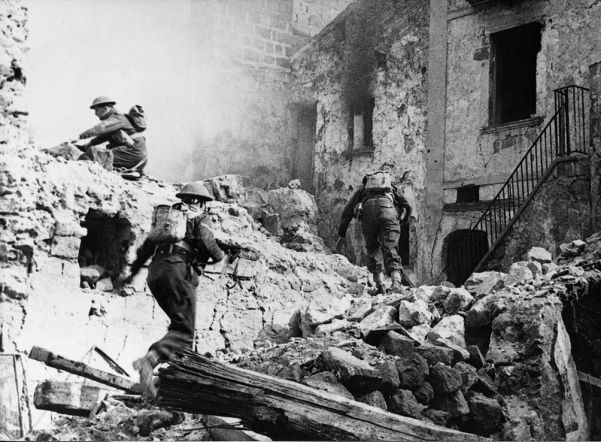 Infantry of the British 4th Division pick their way through shattered streets during the advance to the Rapido River in Italy